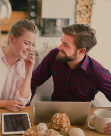source-de-chaleur-couple-installateur-chauffage-bois couple-dans-salon-avec-insert-cheminee-devant-ordinateur-et-au-telephone-souriant